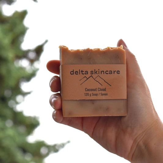 coconut cloud soap held by hand with tree in background