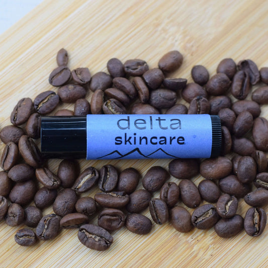 Delta Skincare lip balm with coffee beans on a wooden surface