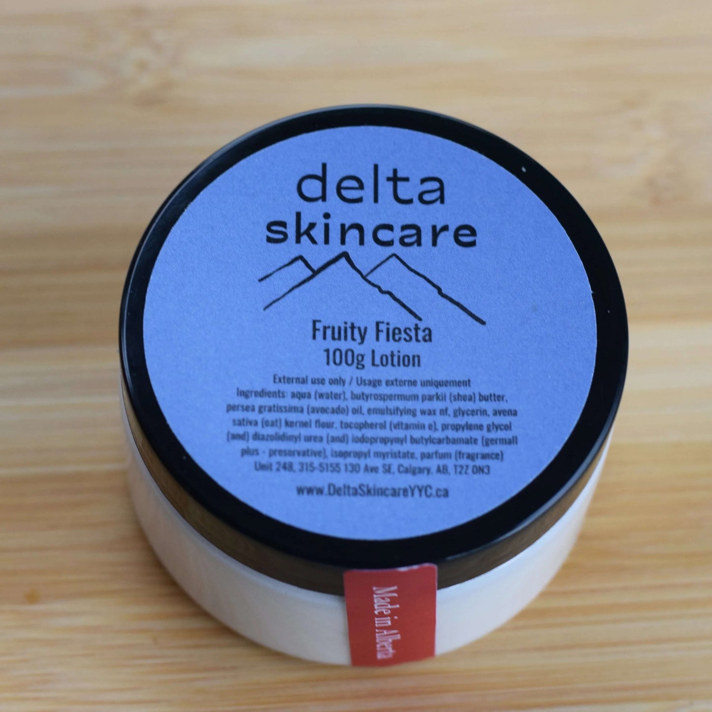 Delta Skincare Fruity Fiesta 100g Lotion container on a wooden surface
