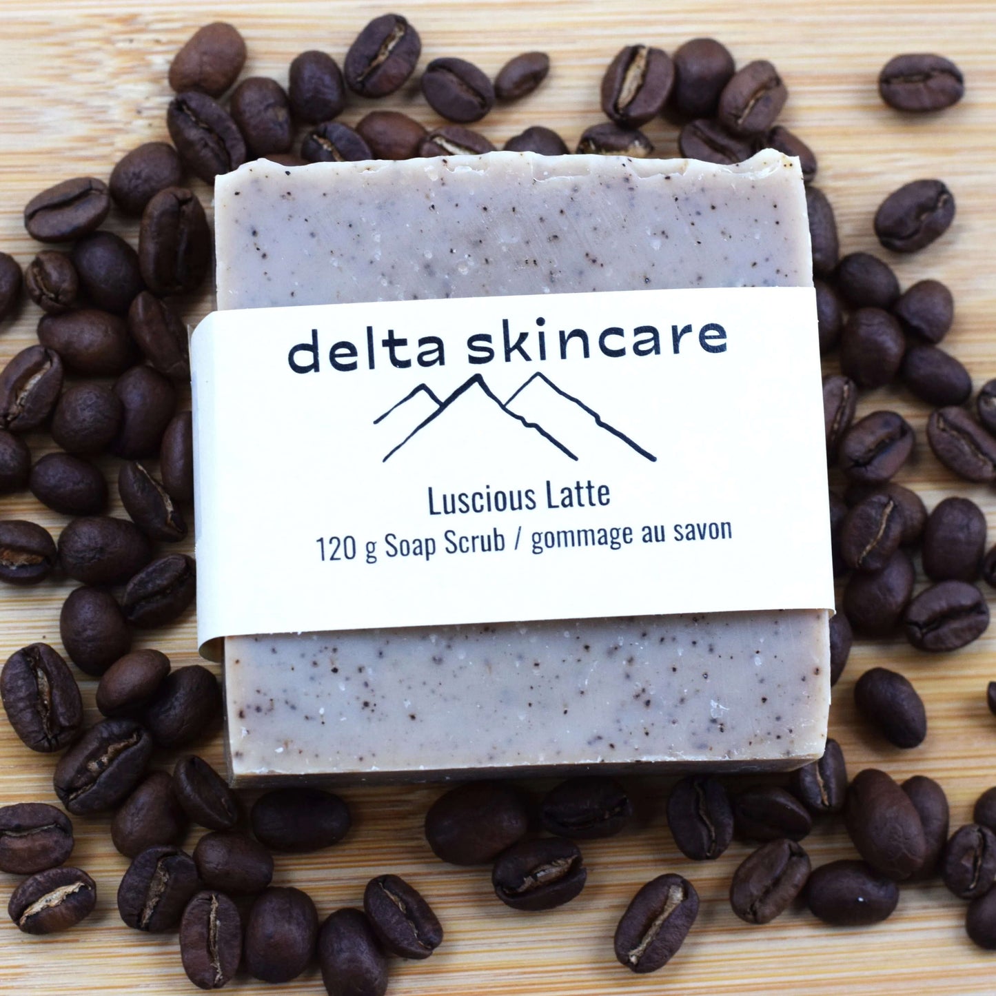Delta Skincare soap bar with 'Luscious Latte' scent surrounded by coffee beans on a wooden surface