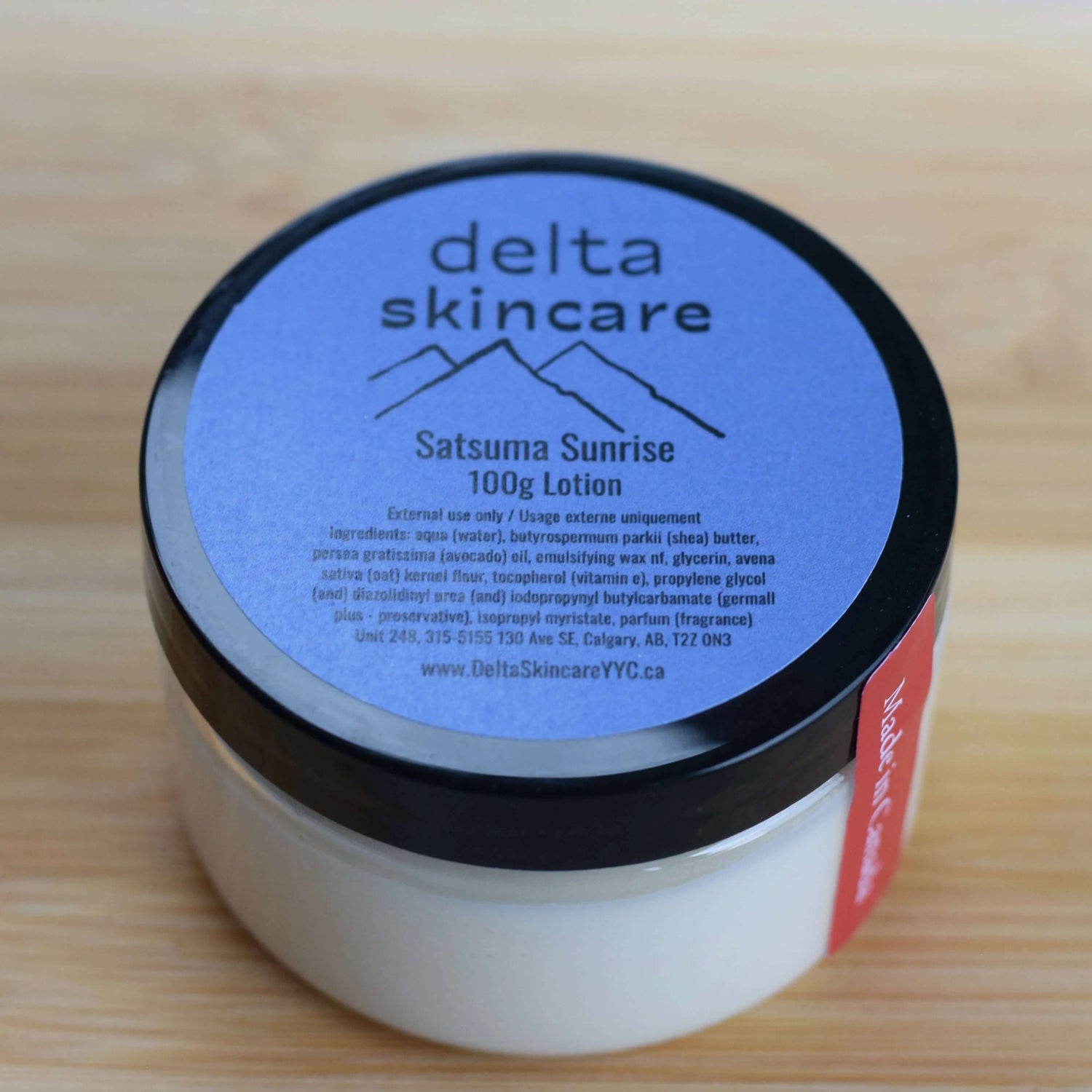 Delta Skincare Satusma Sunrise lotion jar on a wooden surface