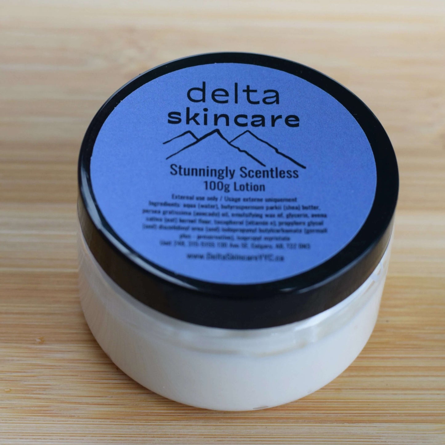 Delta Skincare unscented lotion jar with blue lid on wooden surface