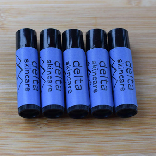 Delta Skincare lip balms with blue labels on a wooden surface