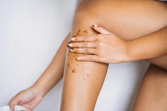 Hand applying coffee scrub to bare leg for skin exfoliation