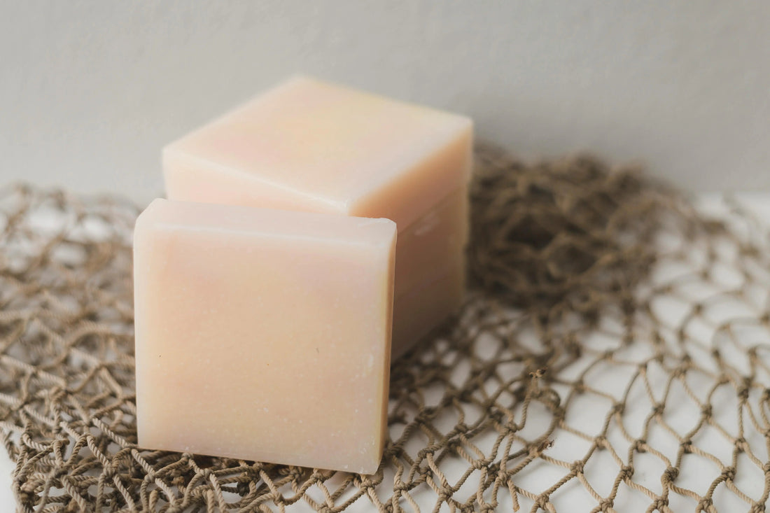 Two natural handmade soap bars on a rustic brown rope mat