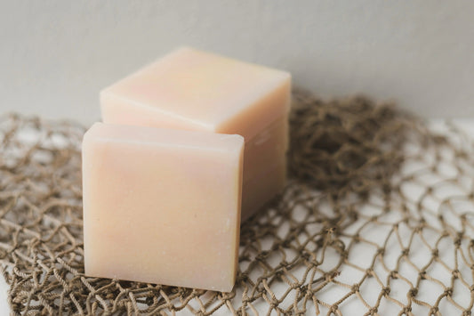 Two natural handmade soap bars on a rustic brown rope mat