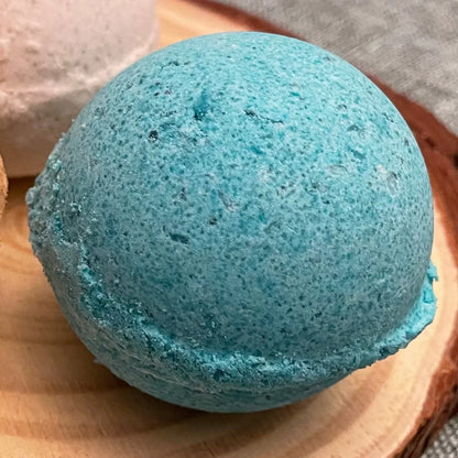 Blue bath bomb on wooden tray, handmade skincare product close up