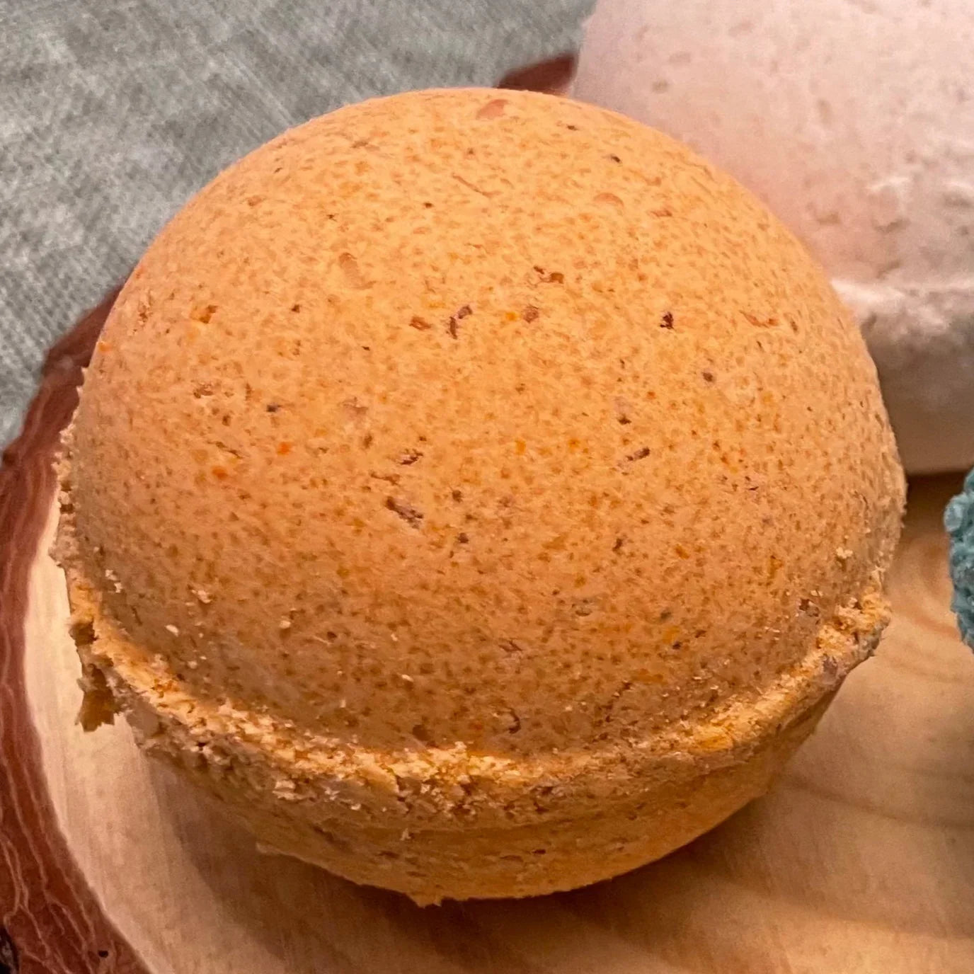 Orange bath bomb on wooden tray with textured surface for spa and relaxation
