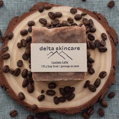 Delta Skincare Luscious Latte soap scrub on wood slice with scattered coffee beans