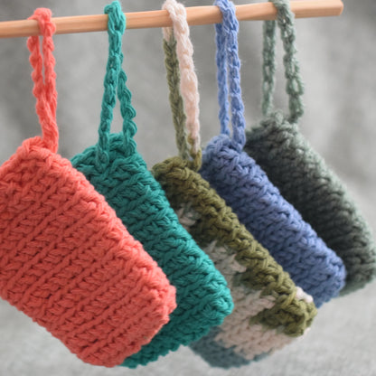 Handmade crochet cotton washcloths in assorted colors hanging on a wooden rod