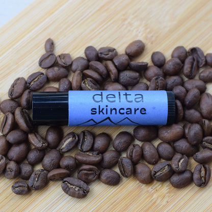 Delta Skincare lip balm with coffee beans on a wooden surface