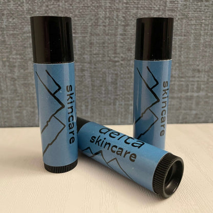 Delta Skincare blue lip balm tubes with mountain design on a white surface