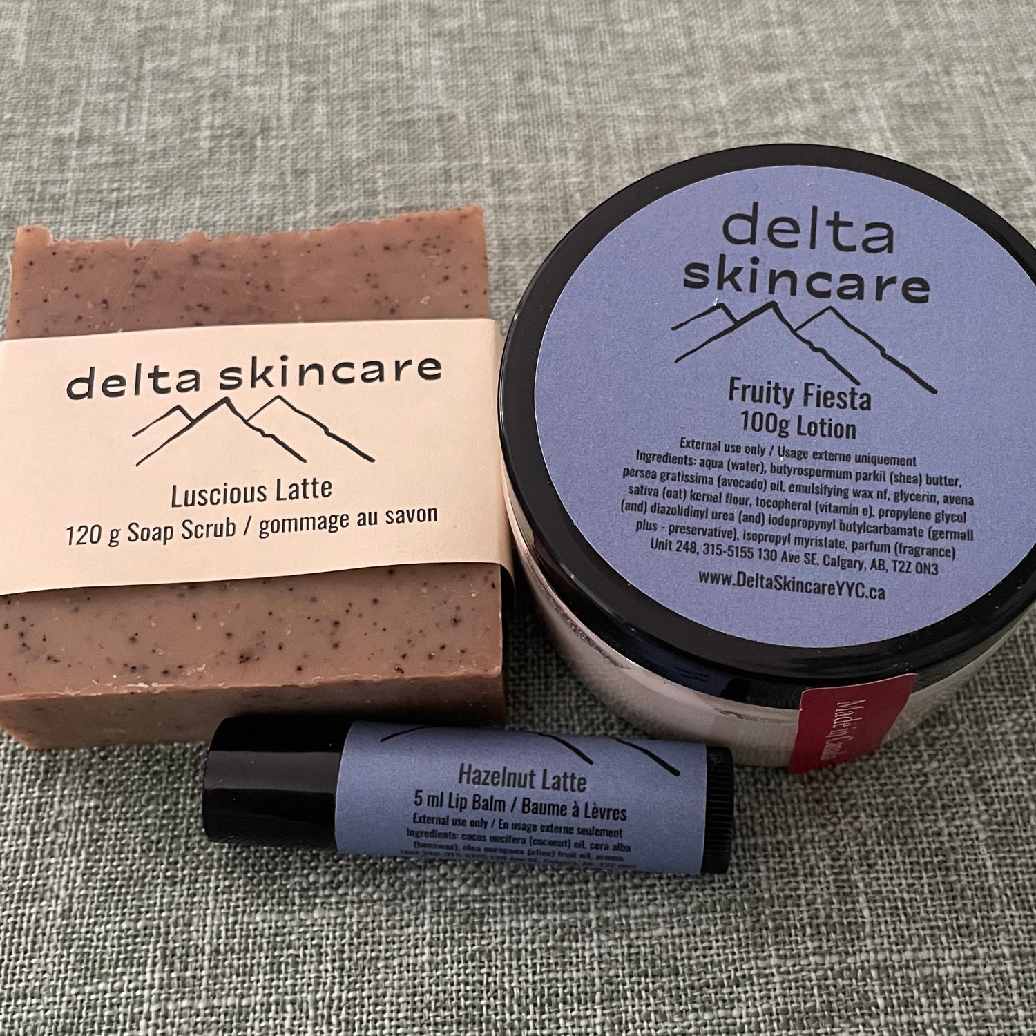 Delta Skincare products including a lotion jar, bar soap, and lip balm on a textured gray surface.