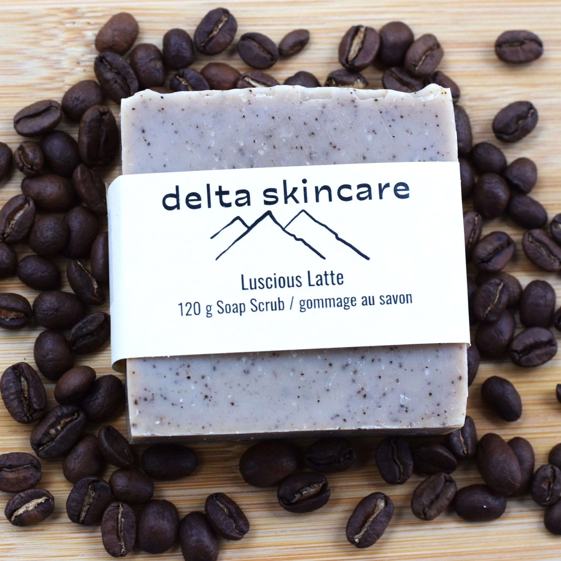 Delta Skincare soap bar with 'Luscious Latte' scent surrounded by coffee beans on a wooden surface